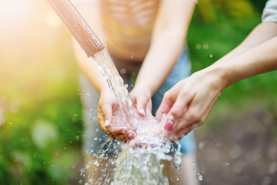Close up view of woman's and child's hands in natural source of water in the park.