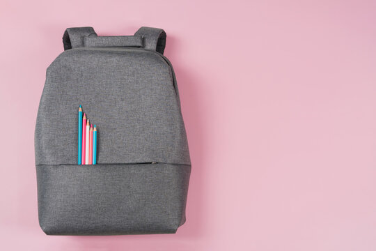 School backpack with colored pencils in light blue, pink, white color on pastel pink background. Education, learning, art concept