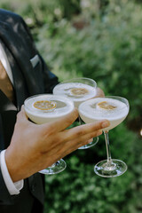 three lemon yellow cocktails in mans hand