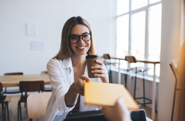 Happy woman with coffee up in hand in canteen