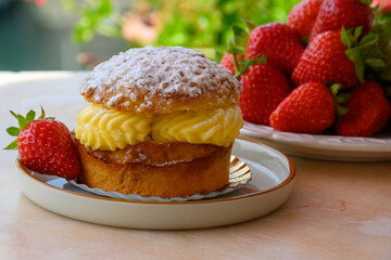 Tarte tropezienne or La Tarte de Saint-Tropez - dessert pastry consisting of filled brioche with cream and fresh berries served outdoor with fresh ripe strawberry