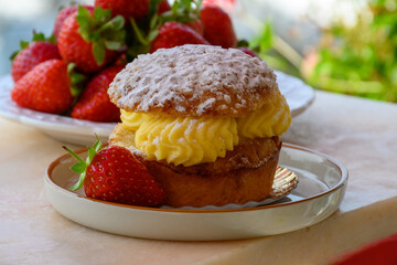 Tarte tropezienne or La Tarte de Saint-Tropez - dessert pastry consisting of filled brioche with cream and fresh berries served outdoor with fresh ripe strawberry