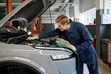 Automobile technician making manual diagnostics checkup of engine for failure
