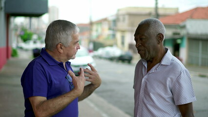 Seniors conversing while standing in city street, candid interaction between elderly diverse people in urban setting