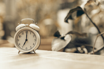 A vintage, white alarm clock showing at early morning, defocused