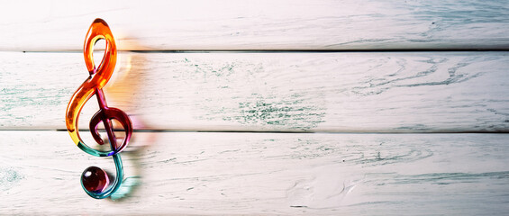 simbolo musicale chiave di violino in vetro colorato su sfondo in legno rustico bianco verde, vista dall'alto