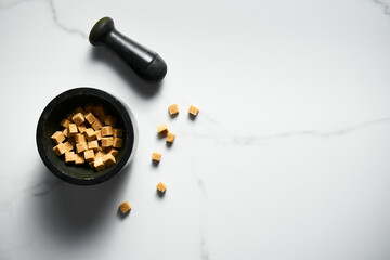 Brown sugar cubes in in a pail on white marble background.