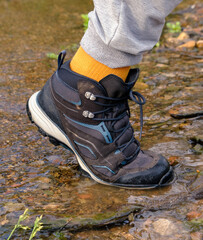 Man wearing outdoor shoes and trekking in a park outdoor by the lake, boots in the lake water