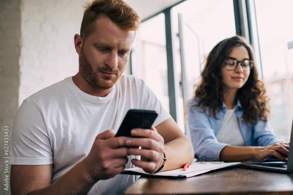 Poster caucasian male using cellphone technology for browsing page in social media networks - connecting to