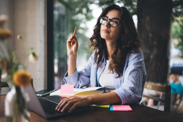 Thoughtful woman working on laptop in cafe