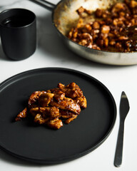 Chicken Tocino. Chicken in gooey sweet glaze. Caramelised chicken thighs in sweet sauce on black plate.