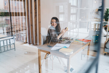 Cheerful female freelancer working on netbook from home