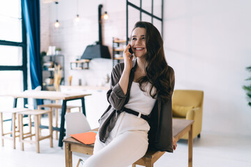 Positive woman having phone conversation in modern apartment