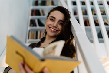 Joyful woman studying book at home