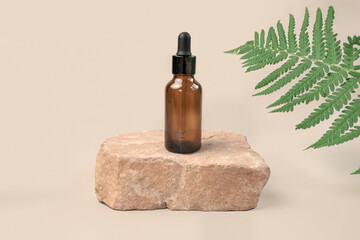Dark amber glass bottle standing on stone. Natural skin care SPA beauty product design. Mineral...