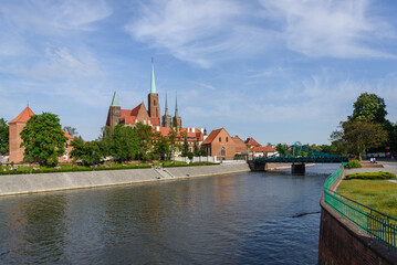 Naklejka premium Outdoor view on the waterside of Oder river and background of Archbishop's Palace, Collegiate Church of the Holy Cross and St. Bartholomew and Wieża Katedry św. Jana Chrzciciela in Wroclaw, Poland.