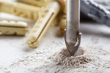 metal drill bit make holes in concrete wall on industrial drilling machine with shavings. Metal...