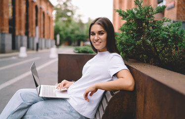 Smiling young woman with laptop in city