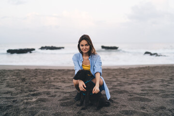 Happy woman sitting on sandy beach with dog