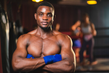 Young muscular african american male boxer looking at camera, wearing boxing gloves, standing isolated over grey background. Sports, workout and bodybuilding concept, confident african american boxer