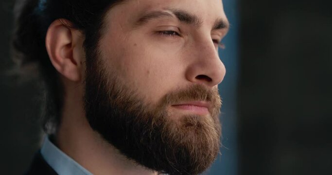 Close up portrait of businessman with beard and long hair, opening his eyes. 