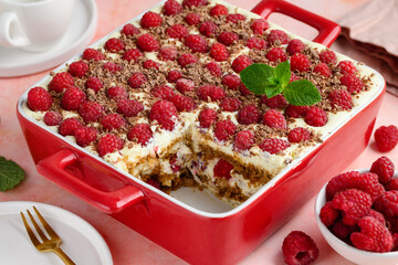 Raspberry tiramisu with chocolate in a red ceramic form. on pink background. Traditional Italian dessert. 
