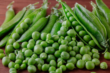 Green pea and pea pods. Pea on wooden table. Closeup of fresh pea. Pea pod with beans.
