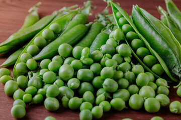 Fototapeta na wymiar Green pea and pea pods. Pea on wooden table. Closeup of fresh pea. Pea pod with beans.