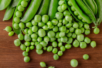 Green pea and pea pods. Pea on wooden table. Closeup of fresh pea. Pea pod with beans.