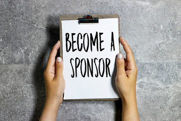 woman hand holding a clipboard with become a sponsor text. Finance and economics concept