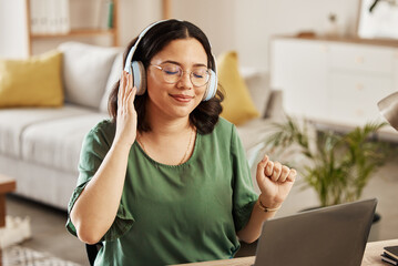 Laptop, music and streaming with a woman in her home, listening to the radio in the living room to relax. Computer, audio and headphones with a young female student in her house for education
