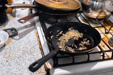 Fried onions in a pan. The process of frying onions on an old gas stove