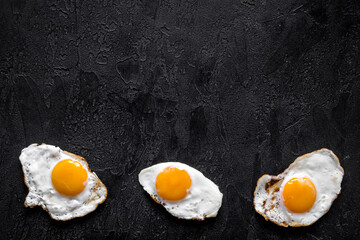 Fried eggs pattern on black background, top view. Breakfast concept