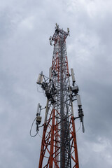Close view of communication cell phone tower shot against cloudy sky. Technology, broadcast, telecommunication, data transmission and outage concept.