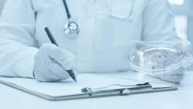The doctor writes a prescription. Describes the disease. Physician's office. Pen in hand. The results of the examination of the patient. Petry dish. Write a research report.