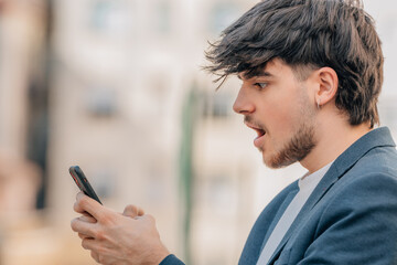 urban young man in the street with mobile phone and expression of astonishment or surprise