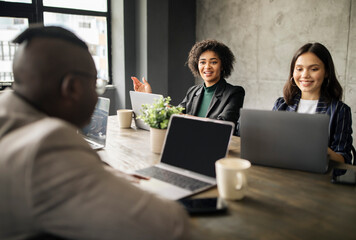 Multiracial Business Women And Man Talking At Table In Office