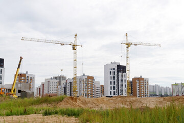 Tower cranes and a multistorey building under construction in a residential area. New modern residential apartment buildings. © Maria