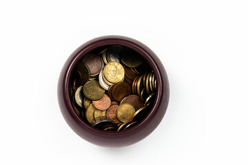 Brown bowl with various coins on white background