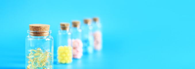 Vitamins in glass bottles on a blue background, side view, copy space. Vitamins, painkillers, healthcare, health pills and dietary supplements. Selective focus
