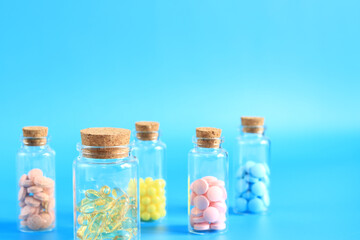 Vitamins in glass bottles on a blue background, side view, copy space. Vitamins, painkillers, healthcare, health pills and dietary supplements. Selective focus