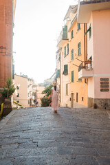 Fototapeta premium Beautiful female model in front he of the colorful city of Riomaggiore, Cinque Terre, Italy