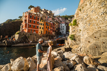 Beautiful traveler couple in front of colorful city of Riomaggiore in Italy, Cinque Terre