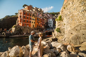 Papier Peint photo Lavable Ligurie Beautiful traveler couple in front of colorful city of Riomaggiore in Italy, Cinque Terre