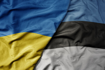 big waving national colorful flag of ukraine and national flag of estonia .