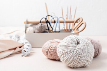 Craft knitting hobby background with yarn in natural colors. Recomforting hobby to reduce stress for cold fall and winter weather. - obrazy, fototapety, plakaty