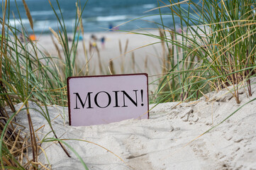 Sign with the German dialect word 'Moin' (Hello) in the sand dunes of an German island in the north...