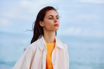 Portrait of a beautiful pensive woman with tanned skin in a white beach shirt with wet hair after...