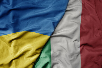 big waving national colorful flag of ukraine and national flag of italy .