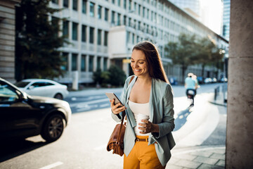 Fototapeta na wymiar Young woman using a smart phone on a city street while having a